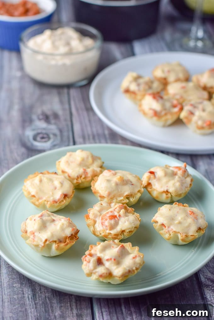 Close up of the green plate of lobster filled phyllo cups with extra cream cheese lobster in the background