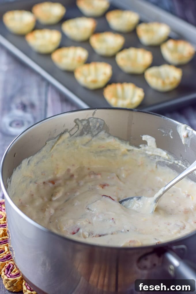 Cooked and melted cream cheese with all the condiments and lobster in a pan with the phyllo tarts in the background