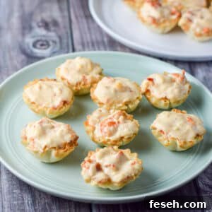 A green plate with phyllo cups filled with lobster and cream cheese - square