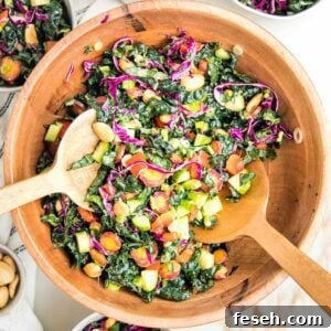 wooden salad bowl filled with colorful chopped salad: tuscan kale, purple carrots, red peppers, purple cabbage, cucumbers and marcona almonds