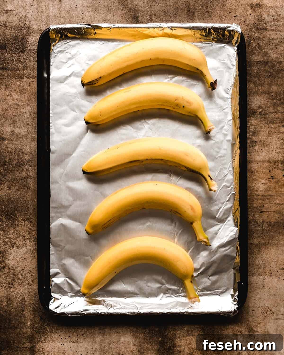 Yellow bananas sitting on a foil covered baking sheet