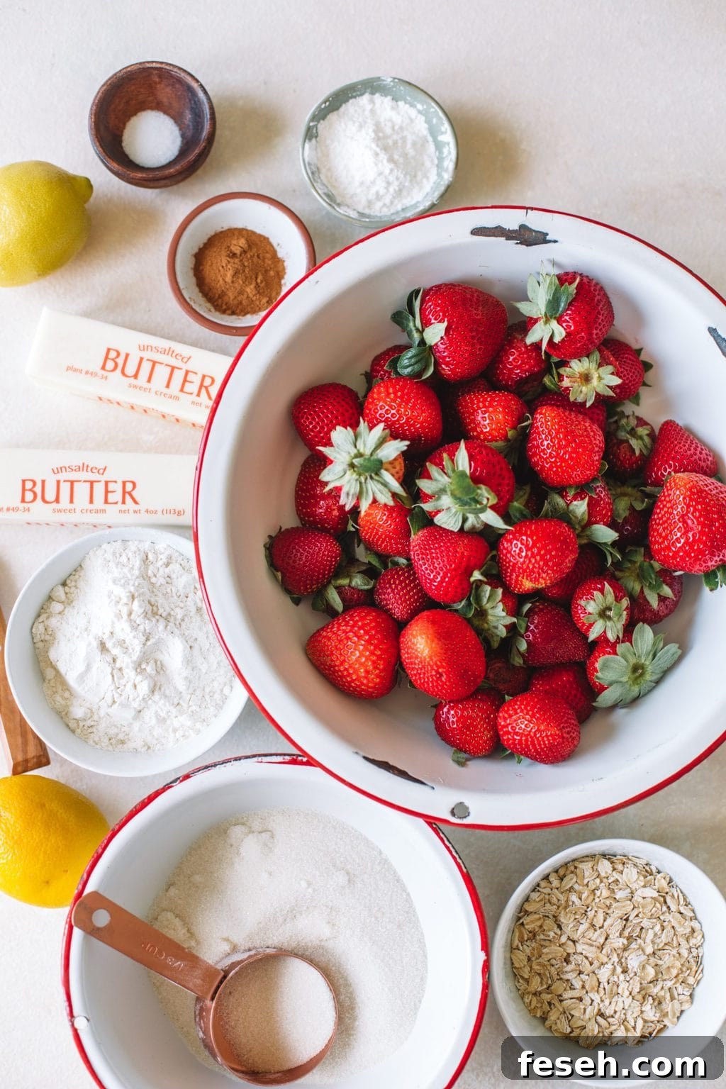 fresh strawberries in white bowl, butter sticks, cinnamon, sugar, flour, cornstarch, oats, lemon