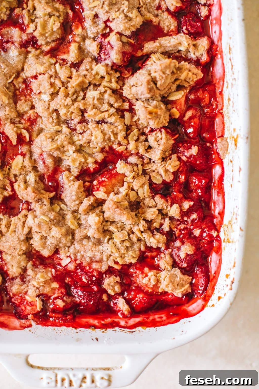 close-up of warm, bubbly strawberry crisp in white casserole dish