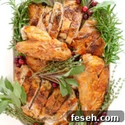 Carved dry brined spatchcock turkey with herb butter on a platter garnished with herbs and cranberries.