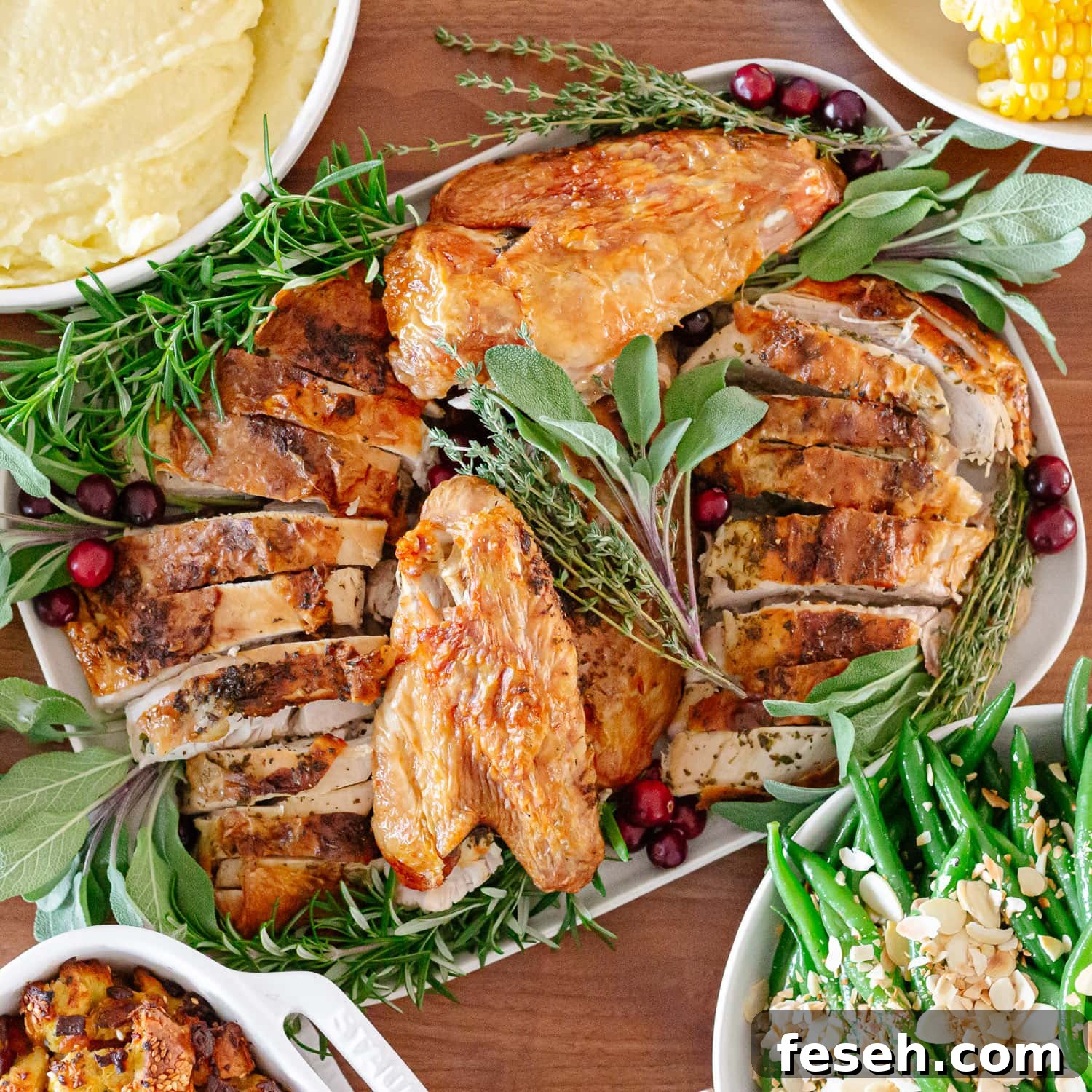 Carved turkey on a platter surrounded by side dishes.