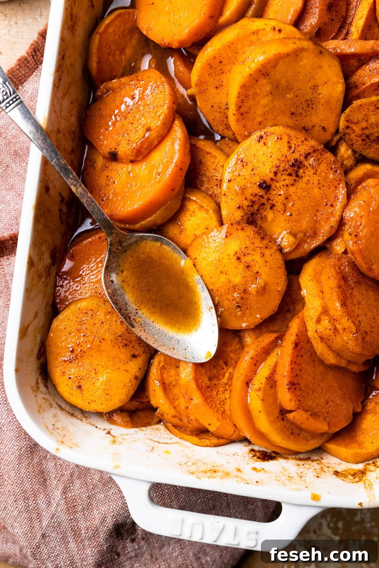 Baking dish with candied sweet potato and a spoon.