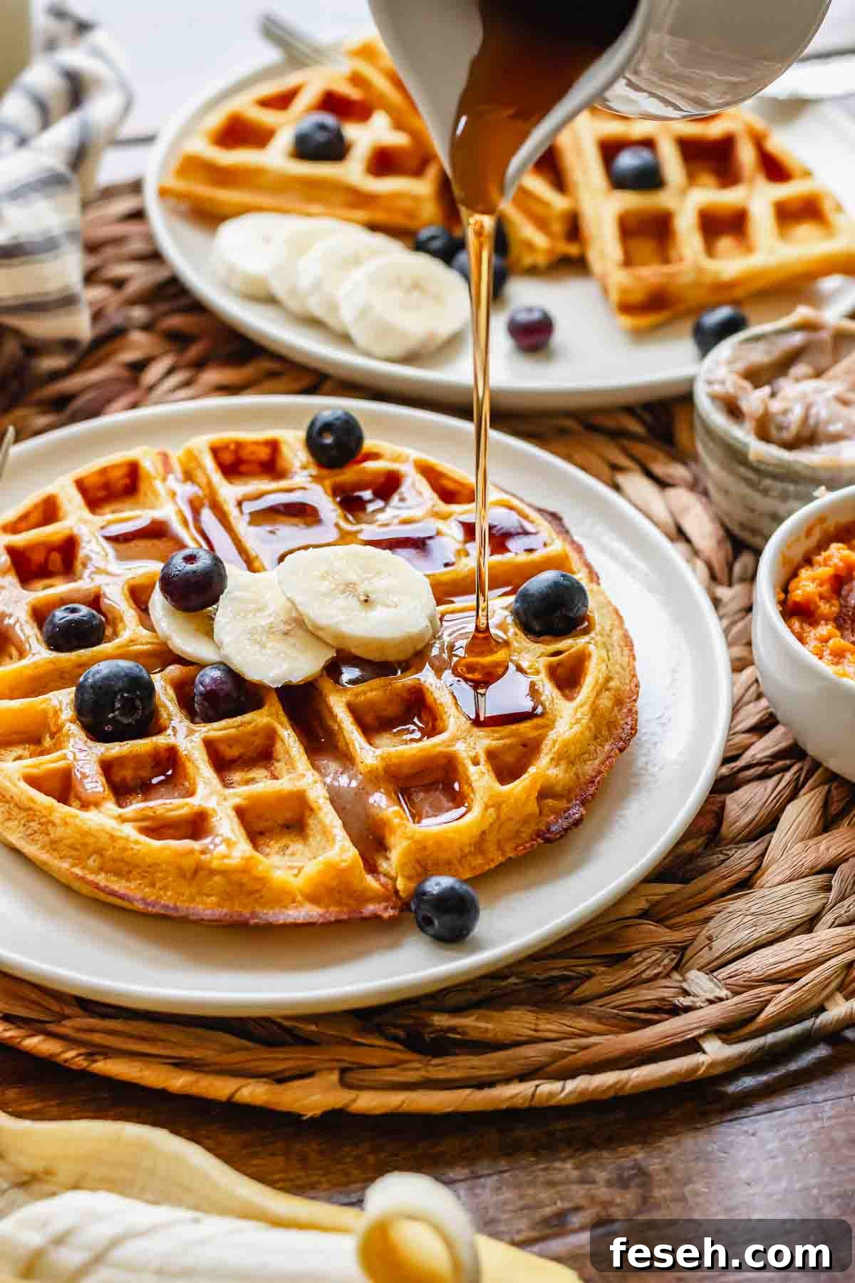 Syrup being poured onto sweet potato waffles.