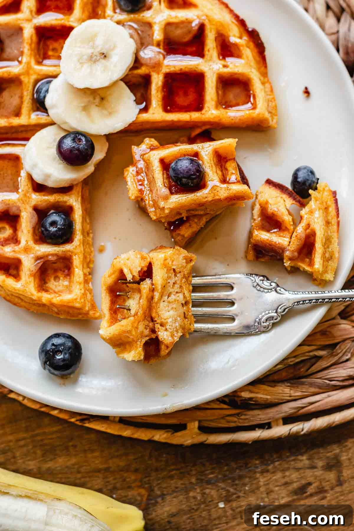 A fork holds two pieces of cut waffles on a plate.