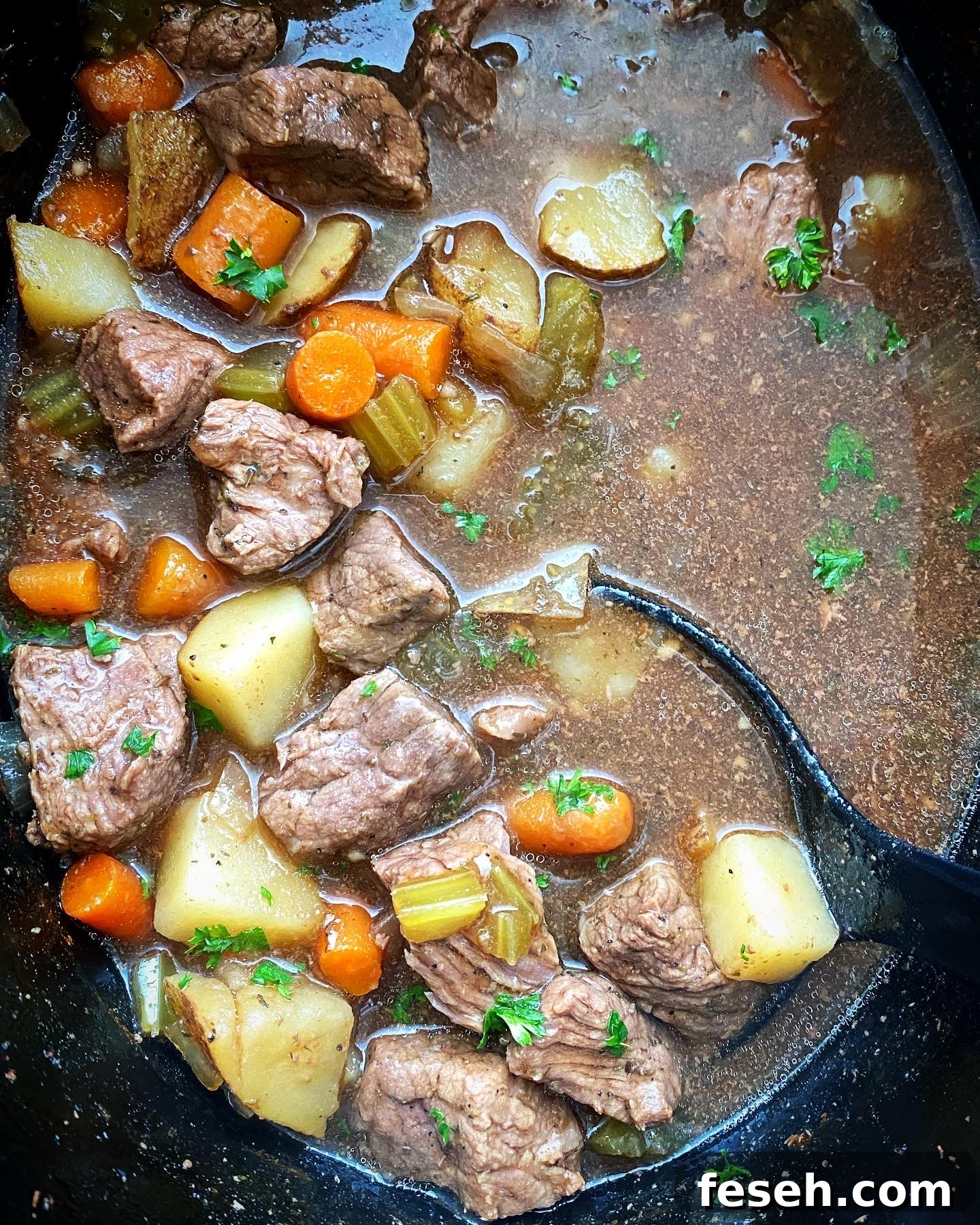 overhead shot of cooked Guinness beef stew in a black slow cooker
