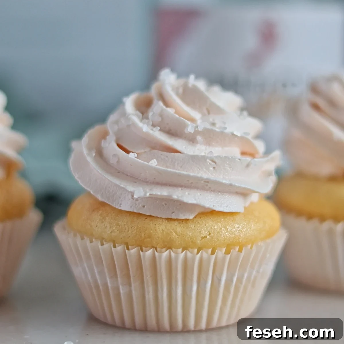three champagne cupcakes in front of empty champagne bottle.