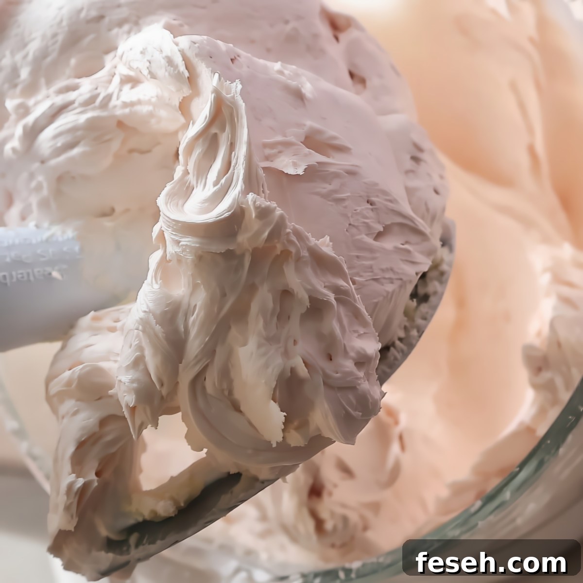 light pink buttercream on beater blade of stand mixer.