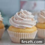 three champagne cupcakes in front of empty champagne bottle.