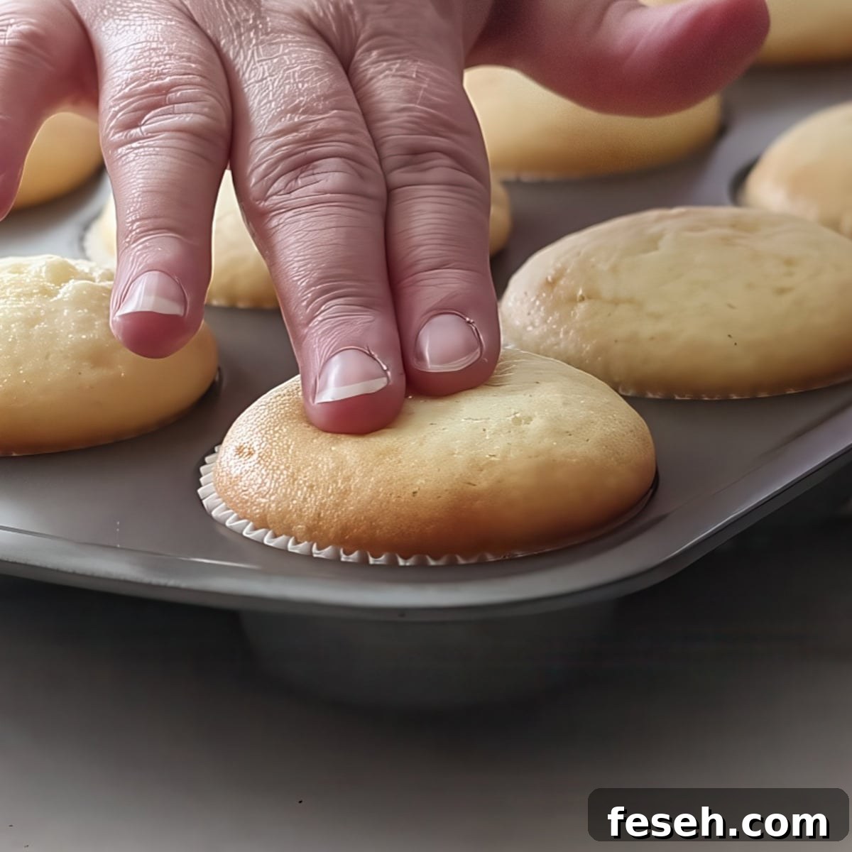 pressing two fingers on baked cupcake in pan.