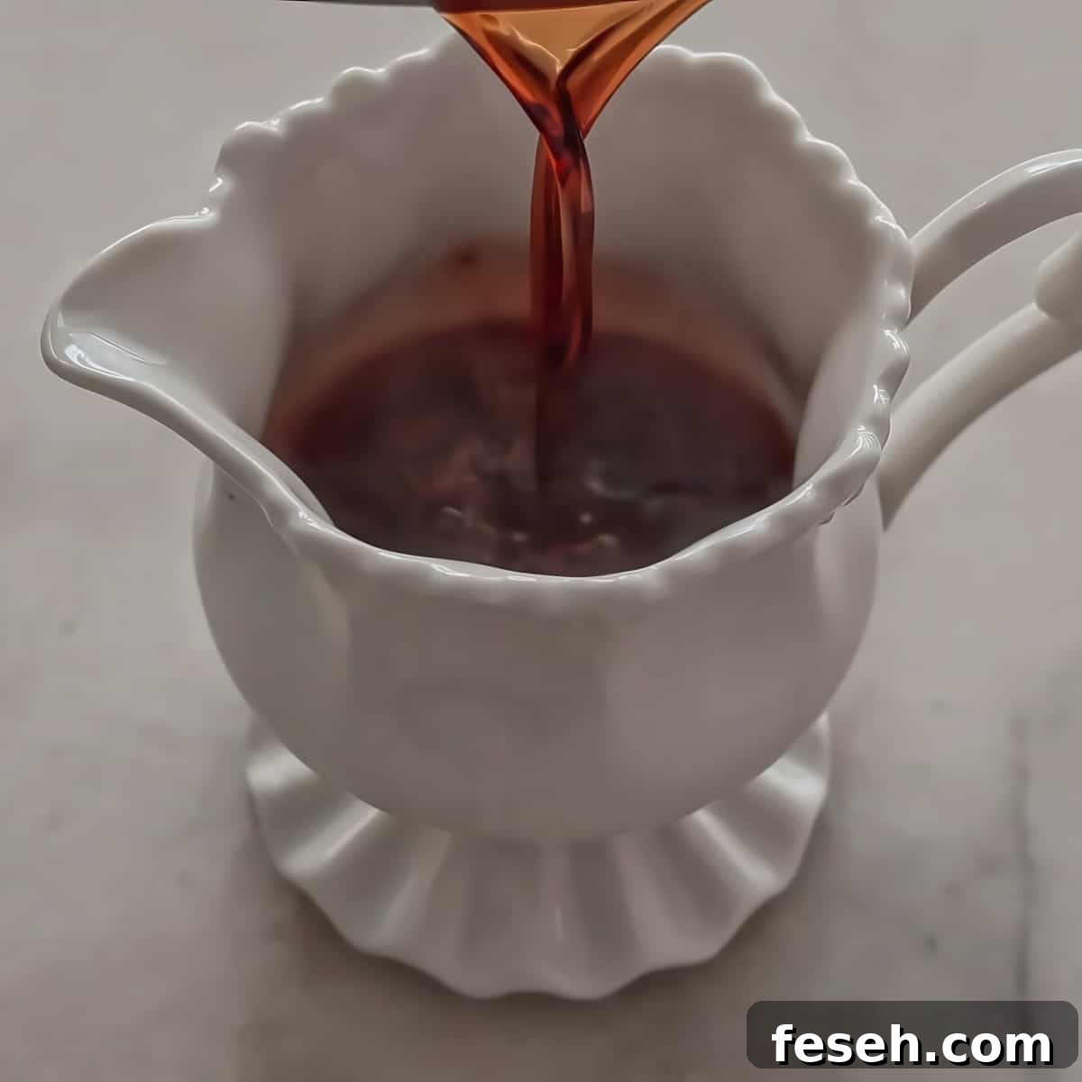 pouring thick brown liquid into small white pitcher.