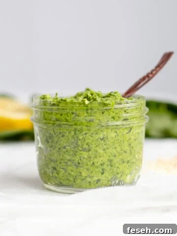 spinach pesto in a mason jar with a small wooden spoon