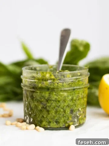 basil pesto in a small mason jar with basil leaves and lemon next to it