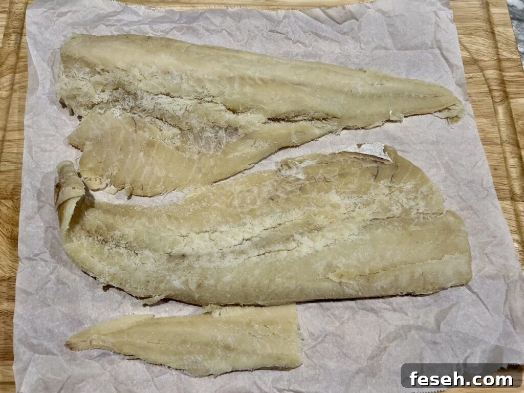 Three pieces of salted, dried cod on parchment paper.