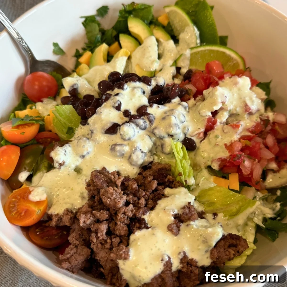 loaded taco salad in a white salad bowl before tossing