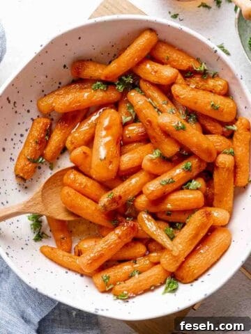 air fryer baby carrots in white bowl with wooden spoon.