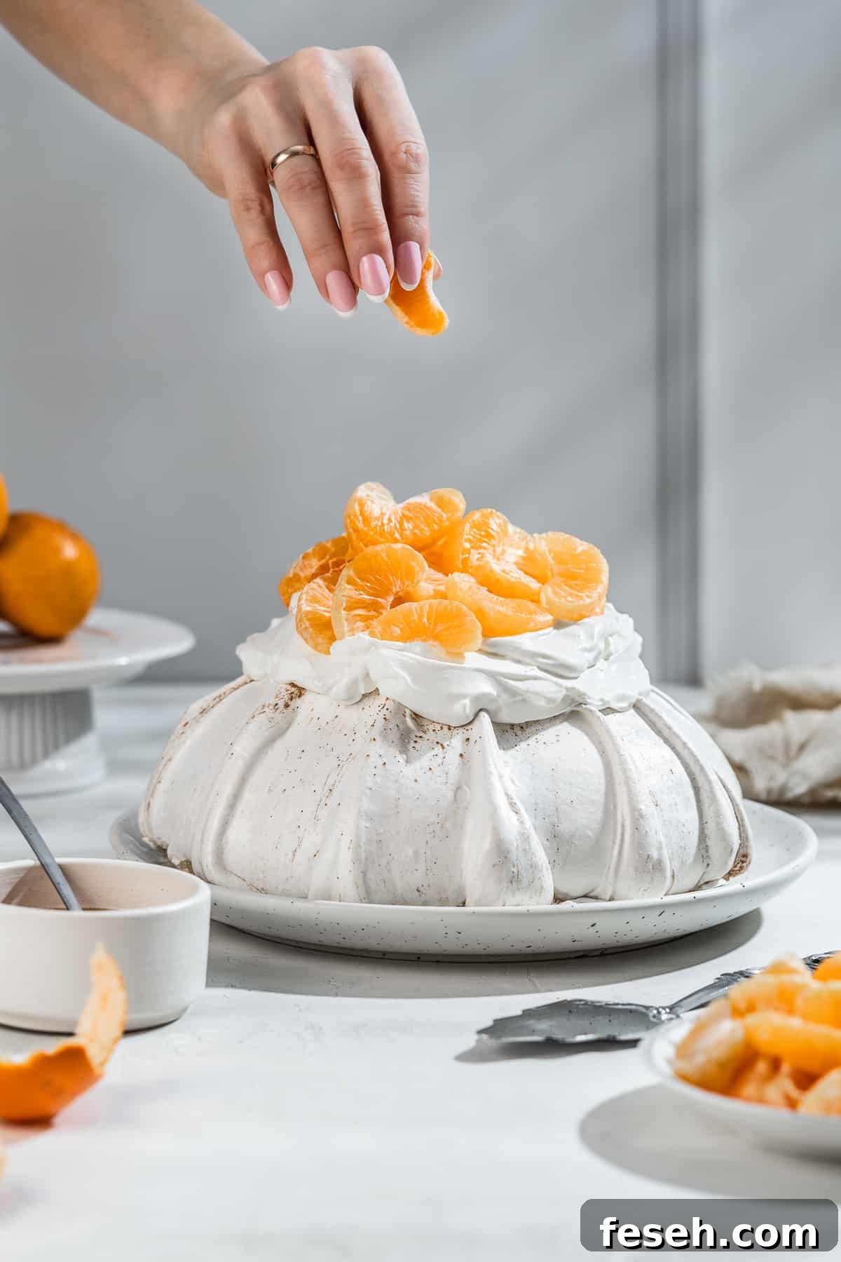 A mandarin wedge in hand above the assembled meringue.