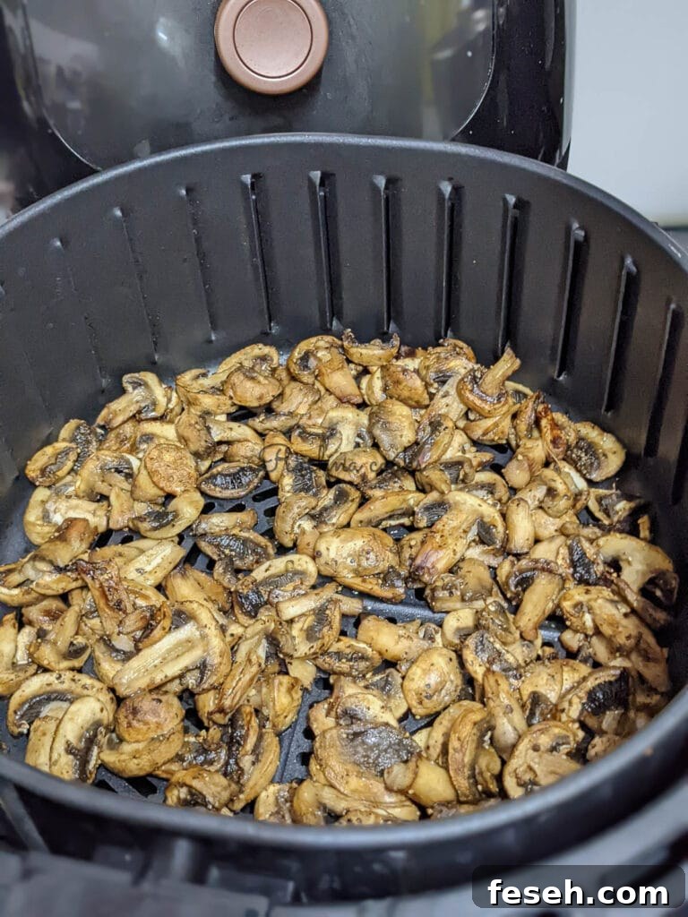 Crispy juicy air fried mushrooms in air fryer basket.