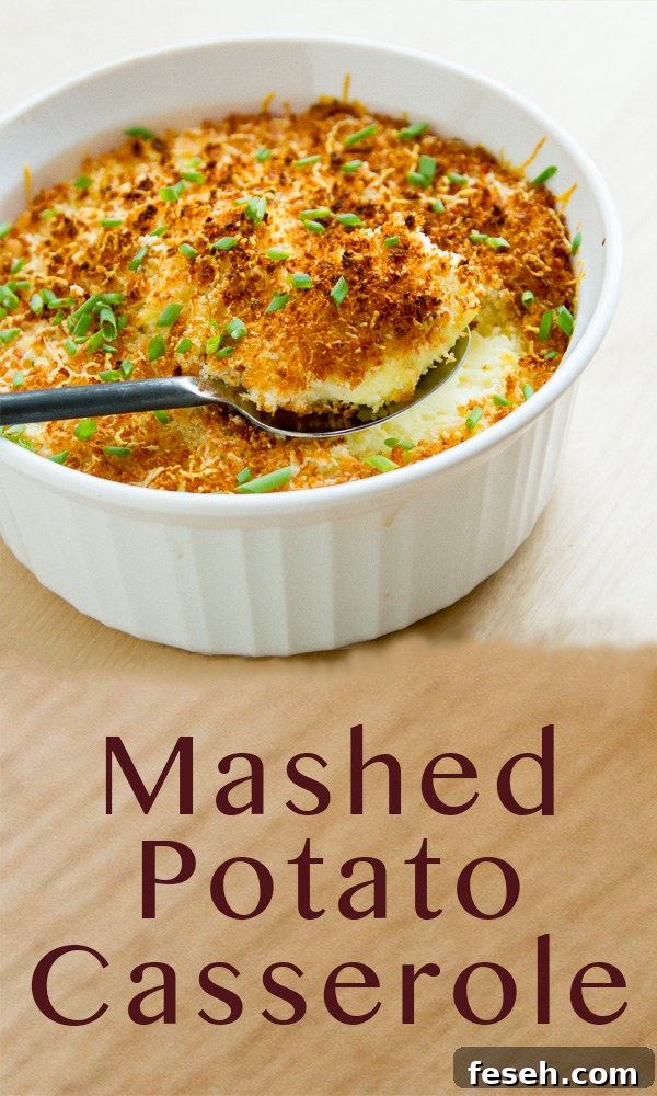 A white casserole dish filled with mashed potato casserole that's being served up with a big spoon.