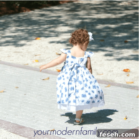A little girl walking on a driveway.