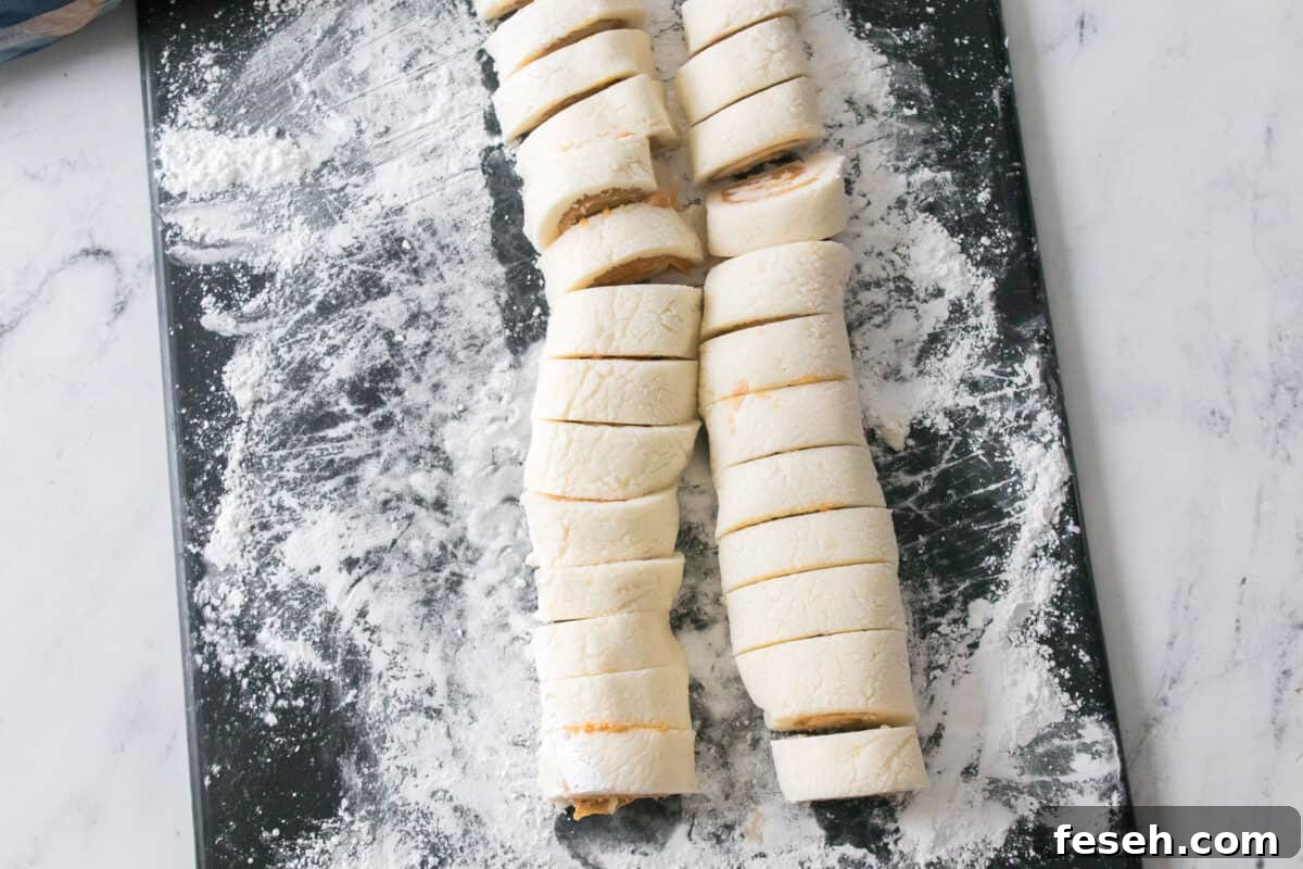 two rolls of potato candy sliced on cutting board with powdered sugar