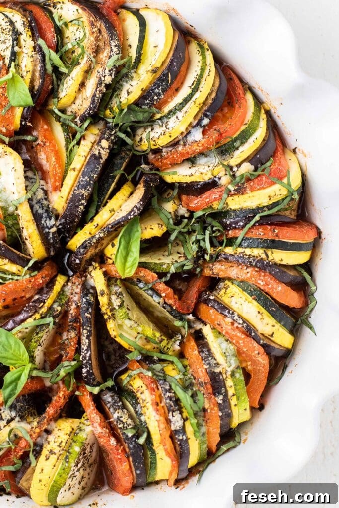 A close up look at a baked ratatouille topped with parmesan and basil.