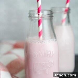 two milk jugs filled with strawberry milk and pink and white straws.