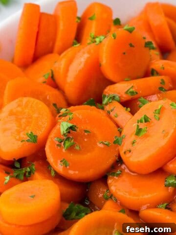 Brown sugar and honey glazed canned carrots, glistening in their syrup and sprinkled with fresh parsley.