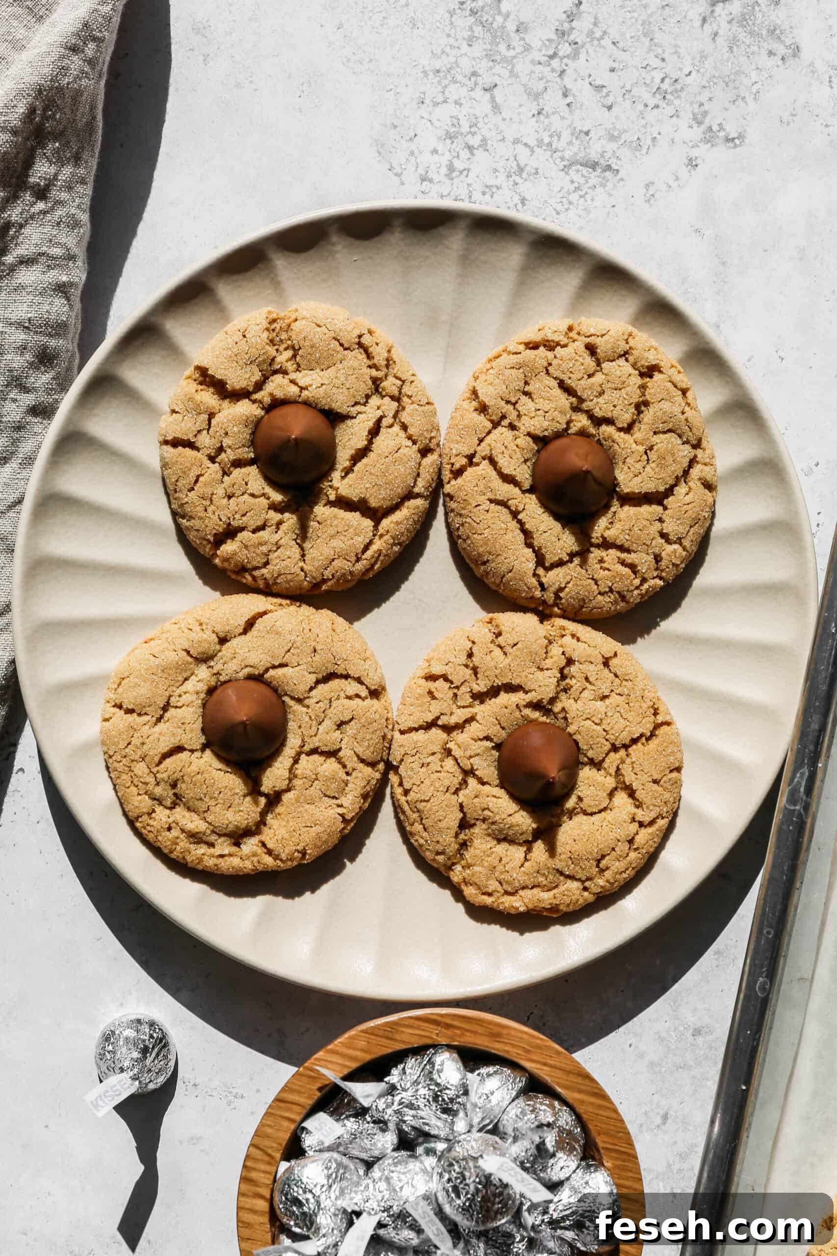 a plate of gluten free peanut butter kiss cookies next to a small bowl of Hershey's kisses.