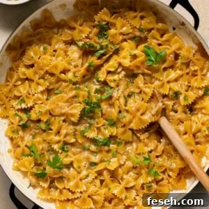 French Onion Pasta in a skillet topped with parsley with a serving spoon