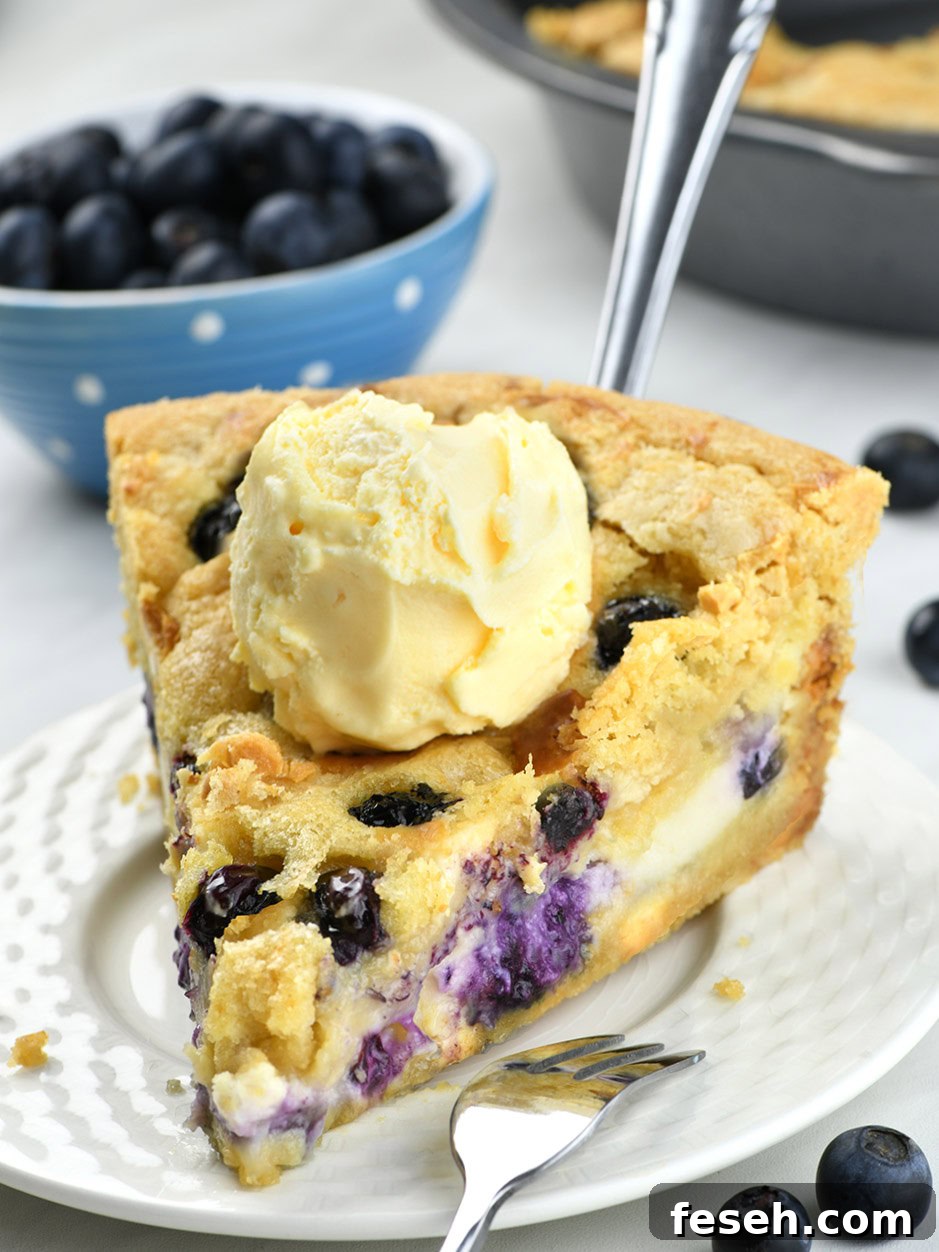 Blueberry Cheesecake Cookie Pie on a white plate with a blueberry jar behind.