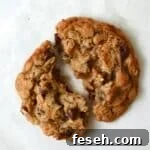 Single serve cowboy cookie broken in half with chocolate chips, coconut, pecans, and oats.