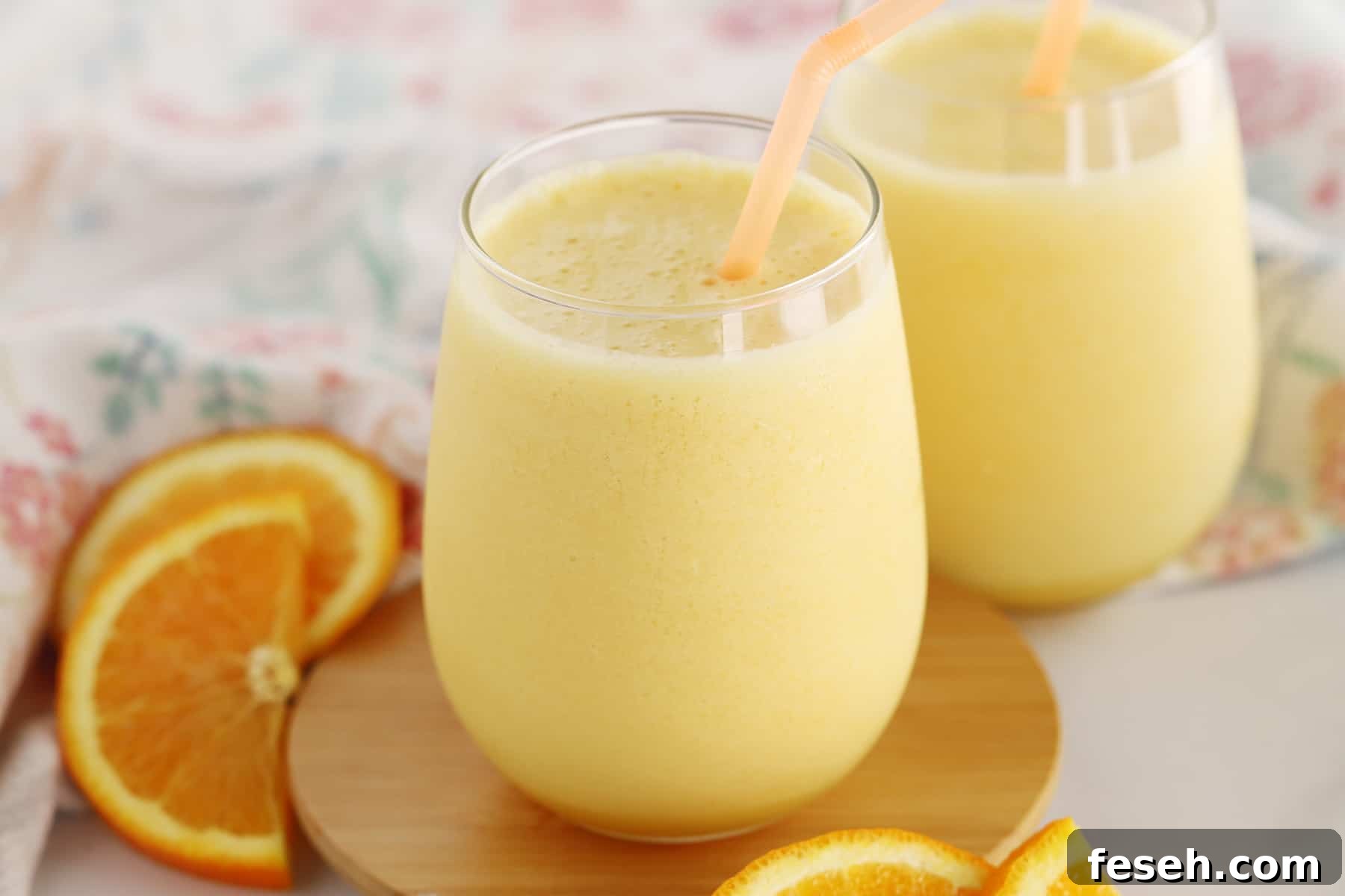 A table with an Orange Julius poured into a glass with a straw. 
