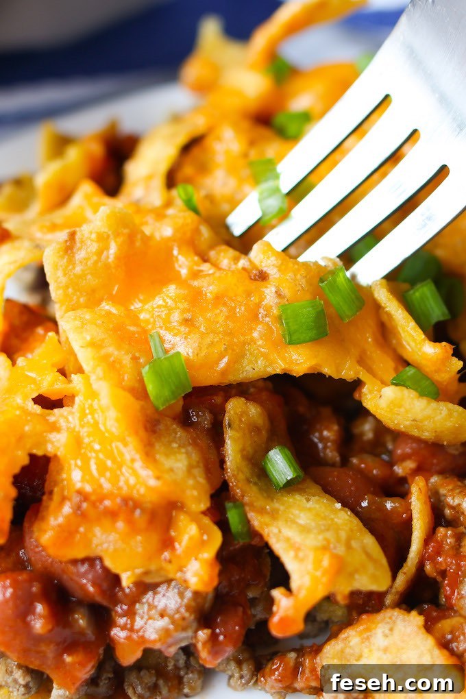 Frito Chili Pie – The best frito pie loaded with Frito corn chips, ground beef, chili beans and tomato sauce. Topped with melted cheddar cheese and more fritos, it is a delicious Mexican-inspired casserole perfect for a quick weeknight dinner!