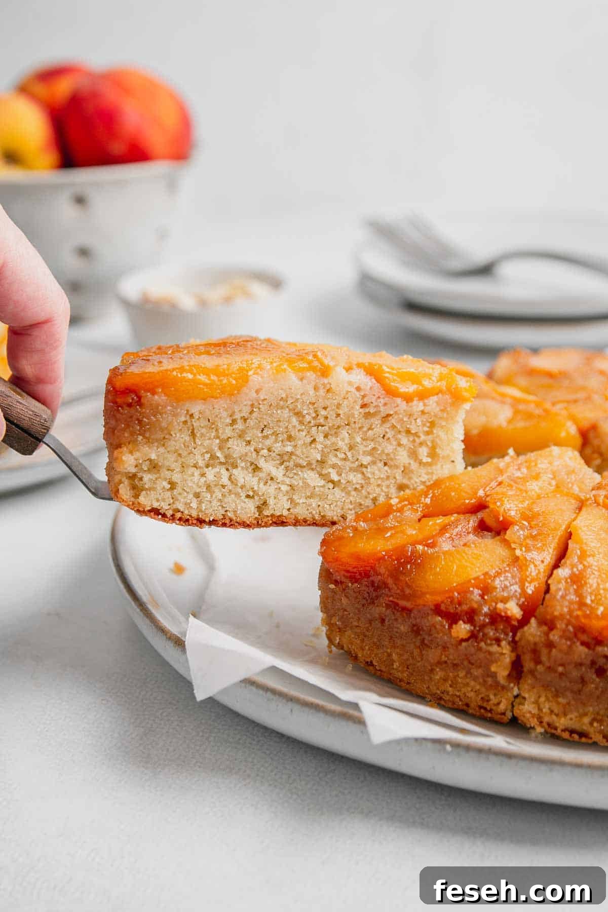 A slice of gluten free peach cake is lifted with a spatula from the rest of the cake.