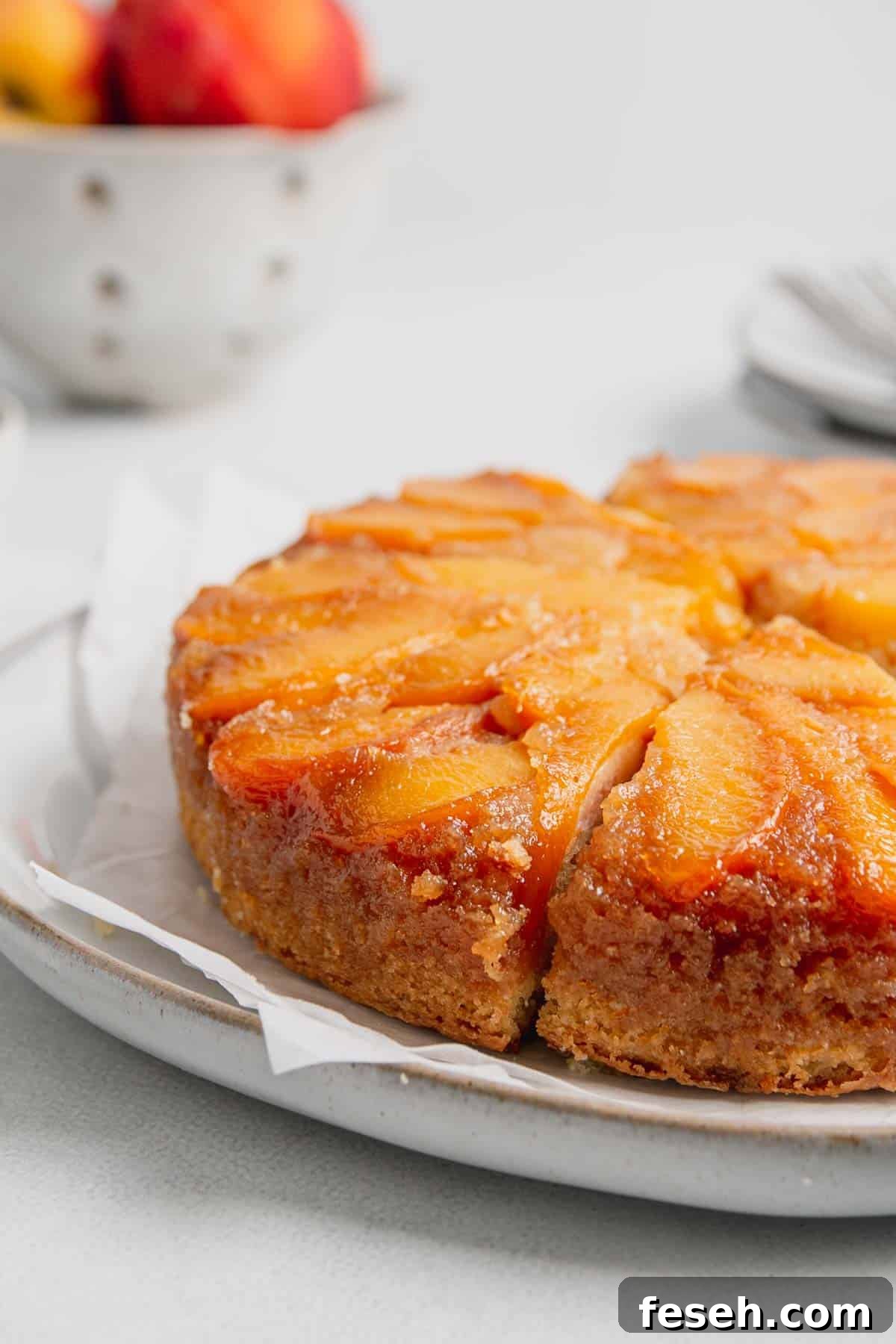 Side view of baked gluten-free peach cake with golden brown edges and gooey peaches on top.