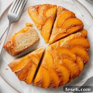 A round gluten-free peach upside down cake cake with peaches arranged on top with some slices cut, one on its side.