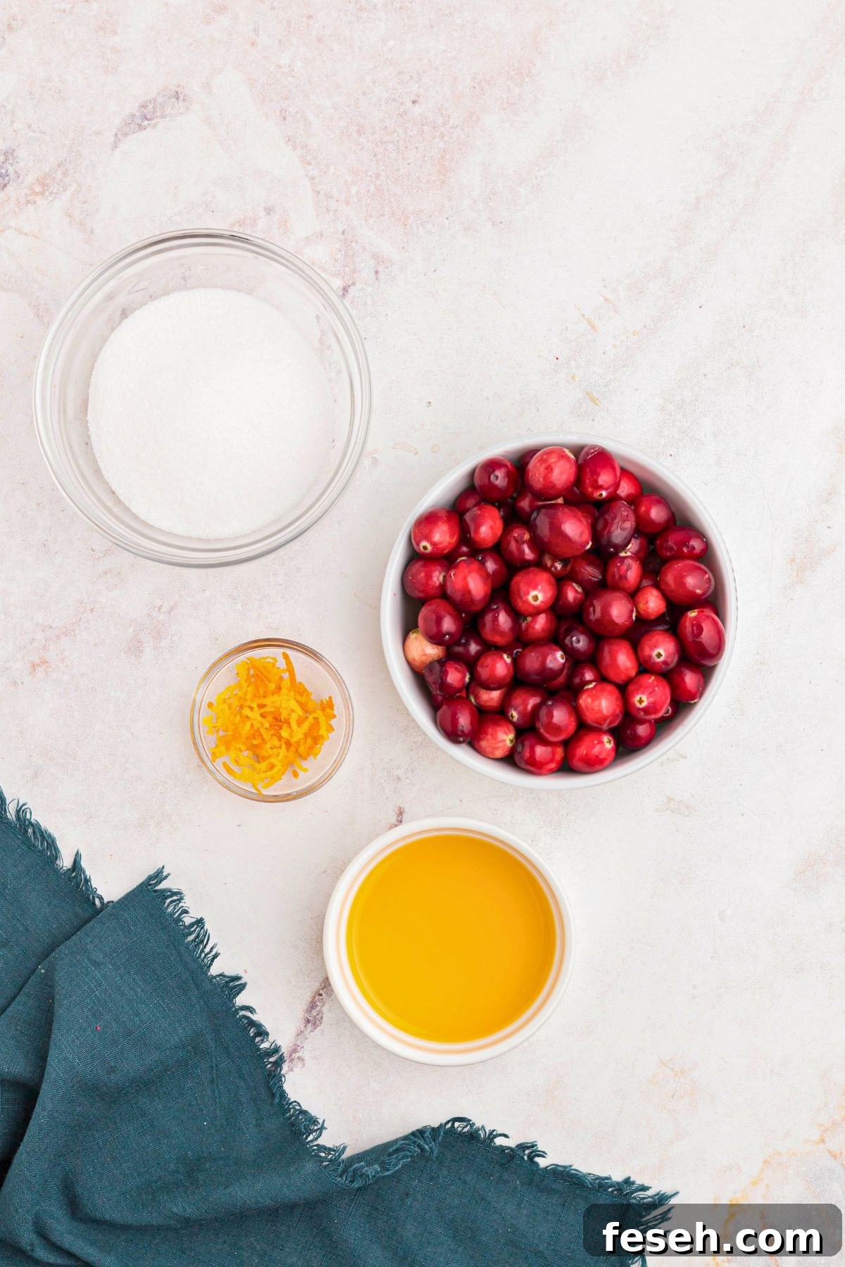 Cranberries, orange juice, orange zest, and sugar, on a marble table. 