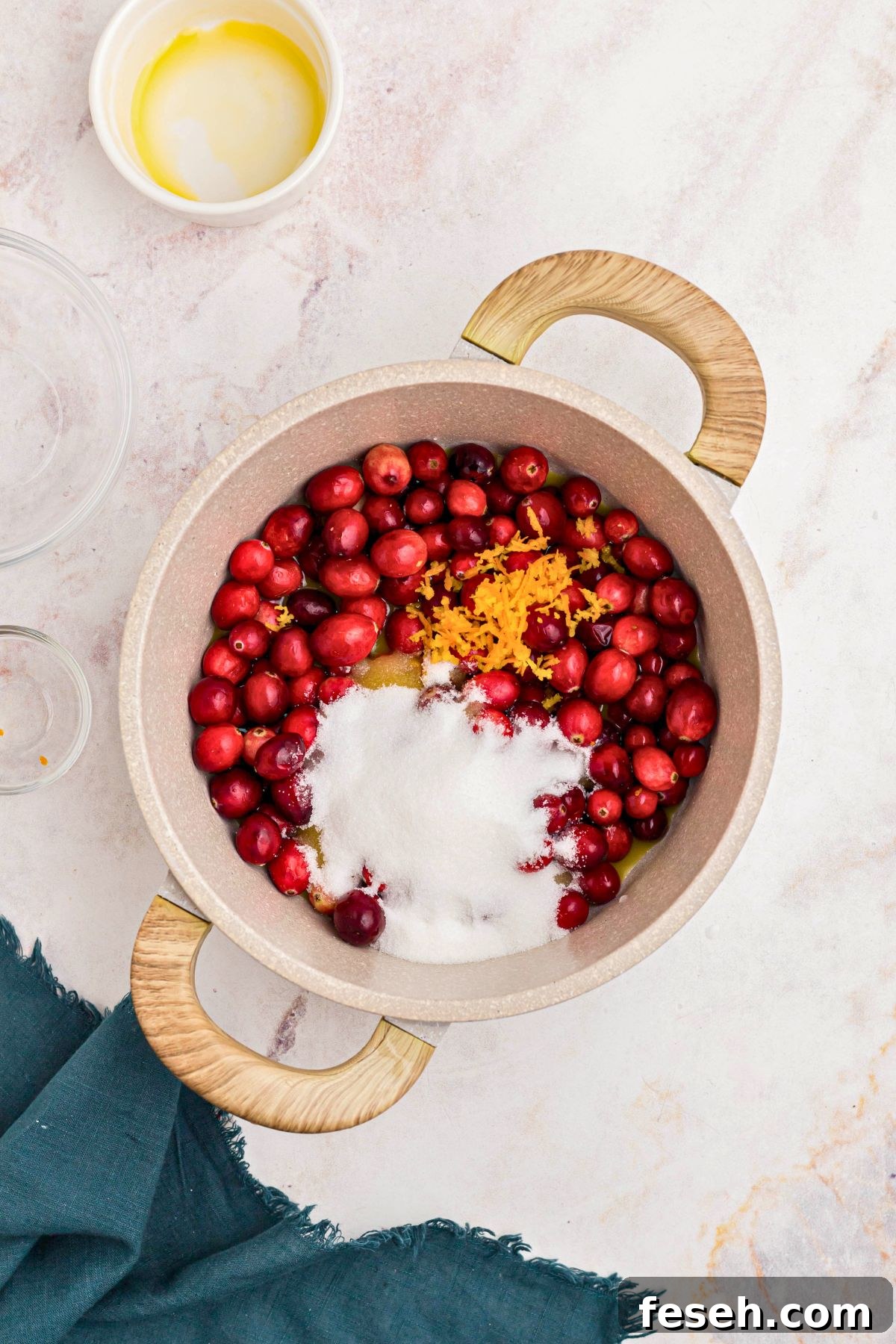 Medium saucepan with fresh cranberries, sugar, and orange juice in the saucepan. 