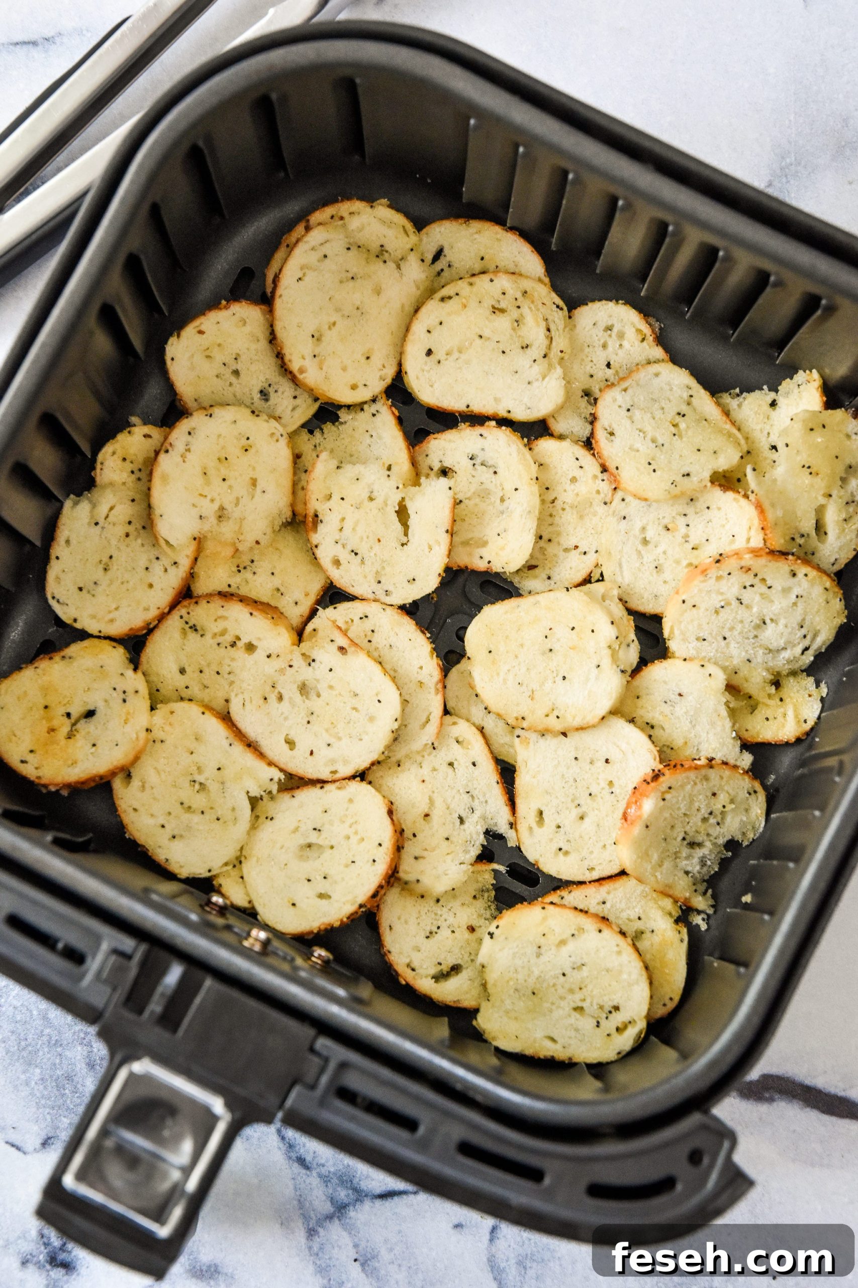 uncooked bagel chips in the air fryer basket ready to be cooked.