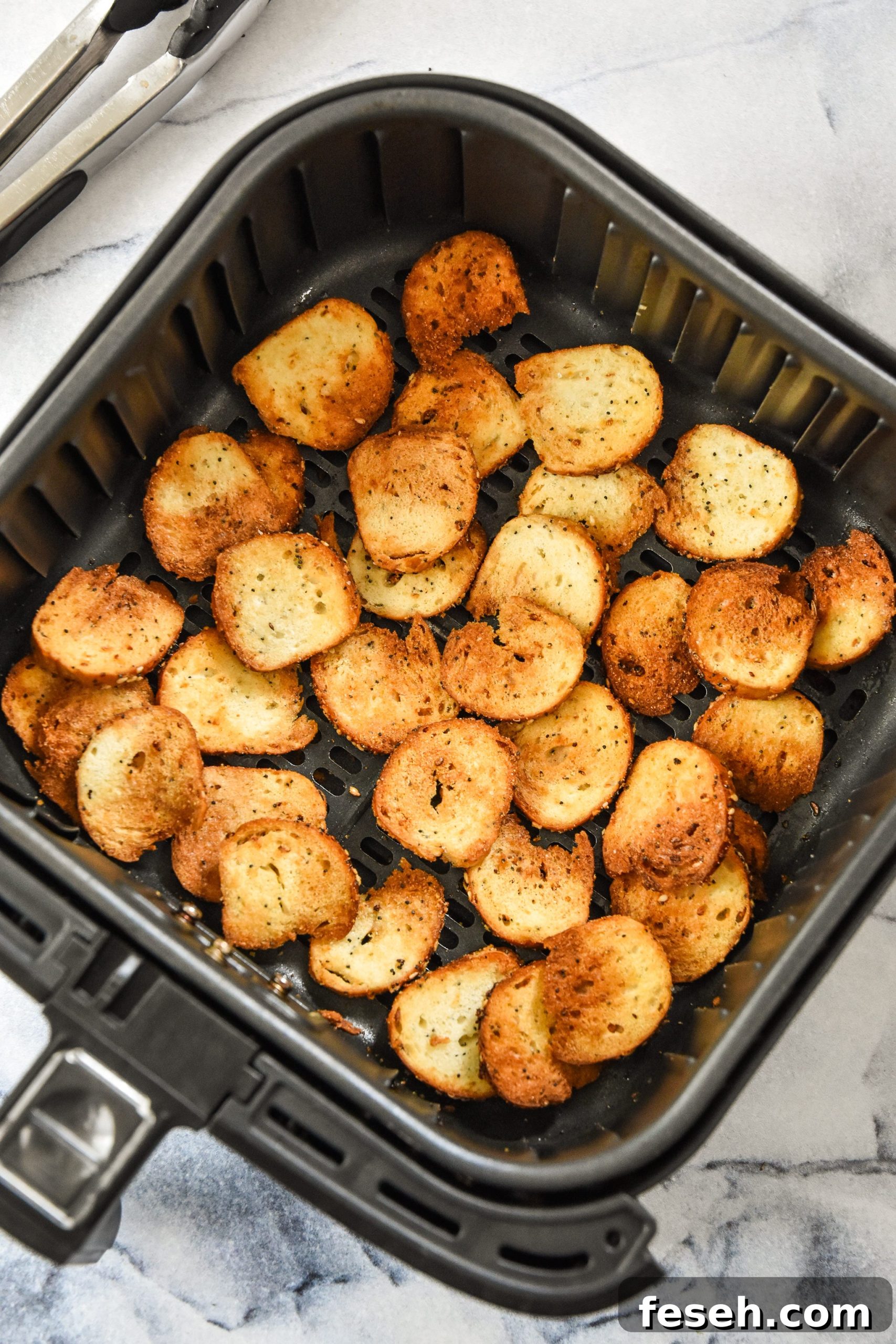 cooked bagel chips in the air fryer basket.