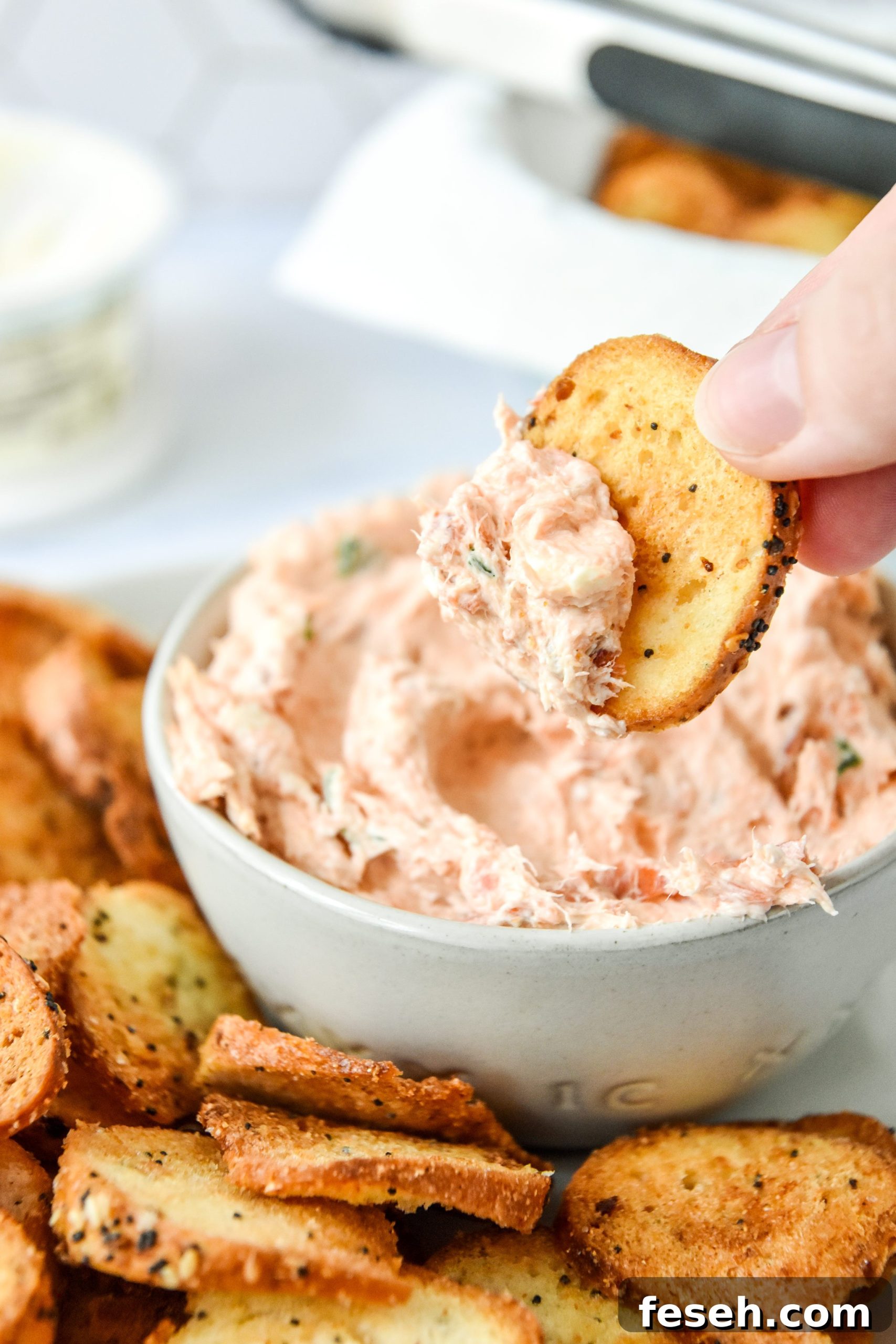 dipping the air fryer everything bagel chip into come cream cheese dip.