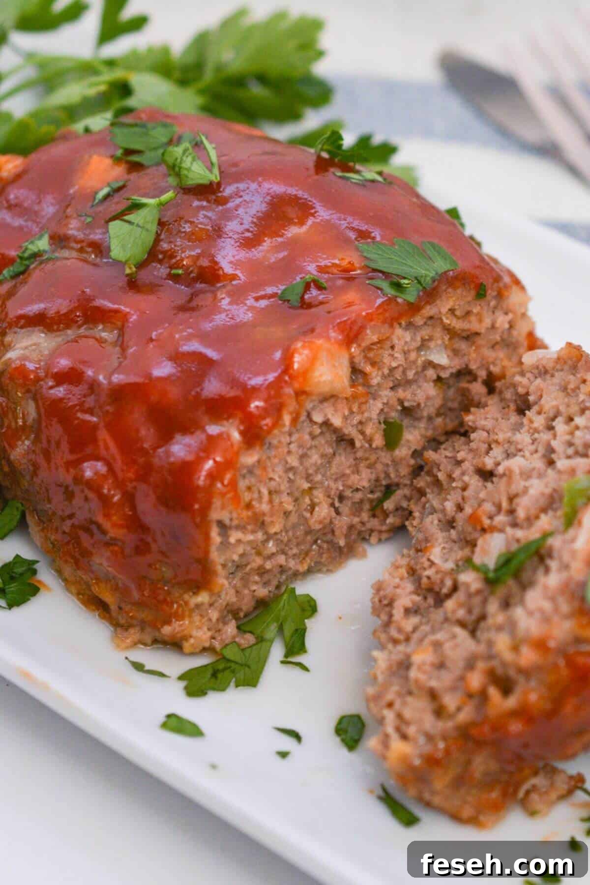 Cracker Barrel meatloaf with sauce and parsley on a white plate.