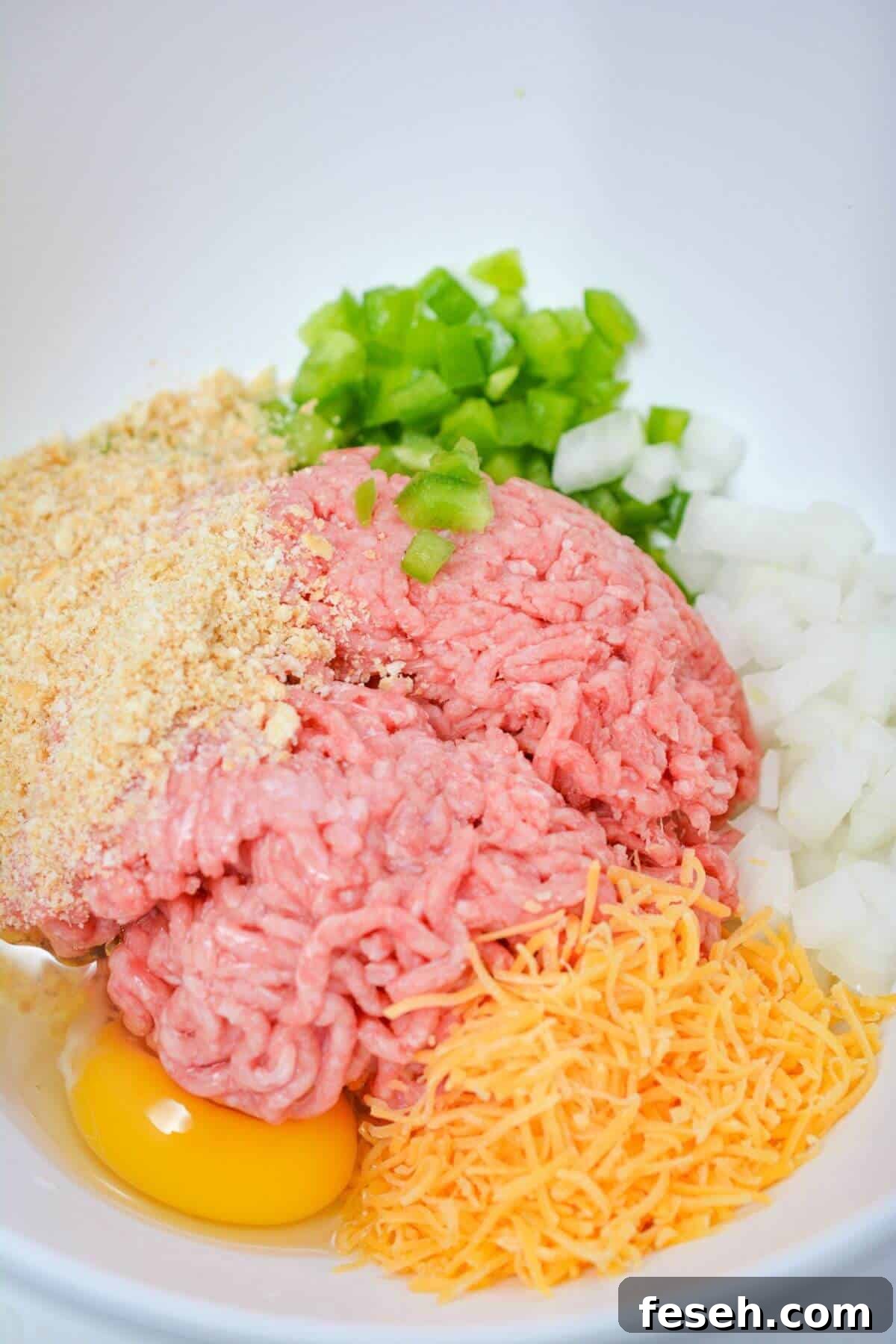 A bowl full of meat, eggs, onions and cheese.