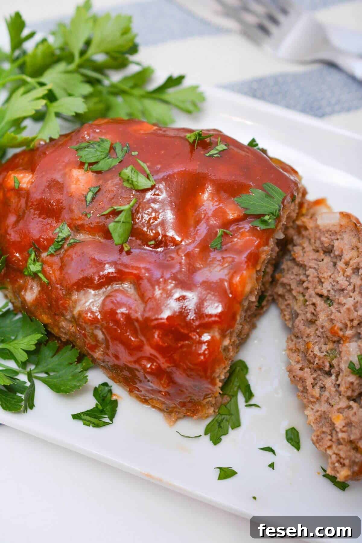 Meatloaf on a white platter with parsley.