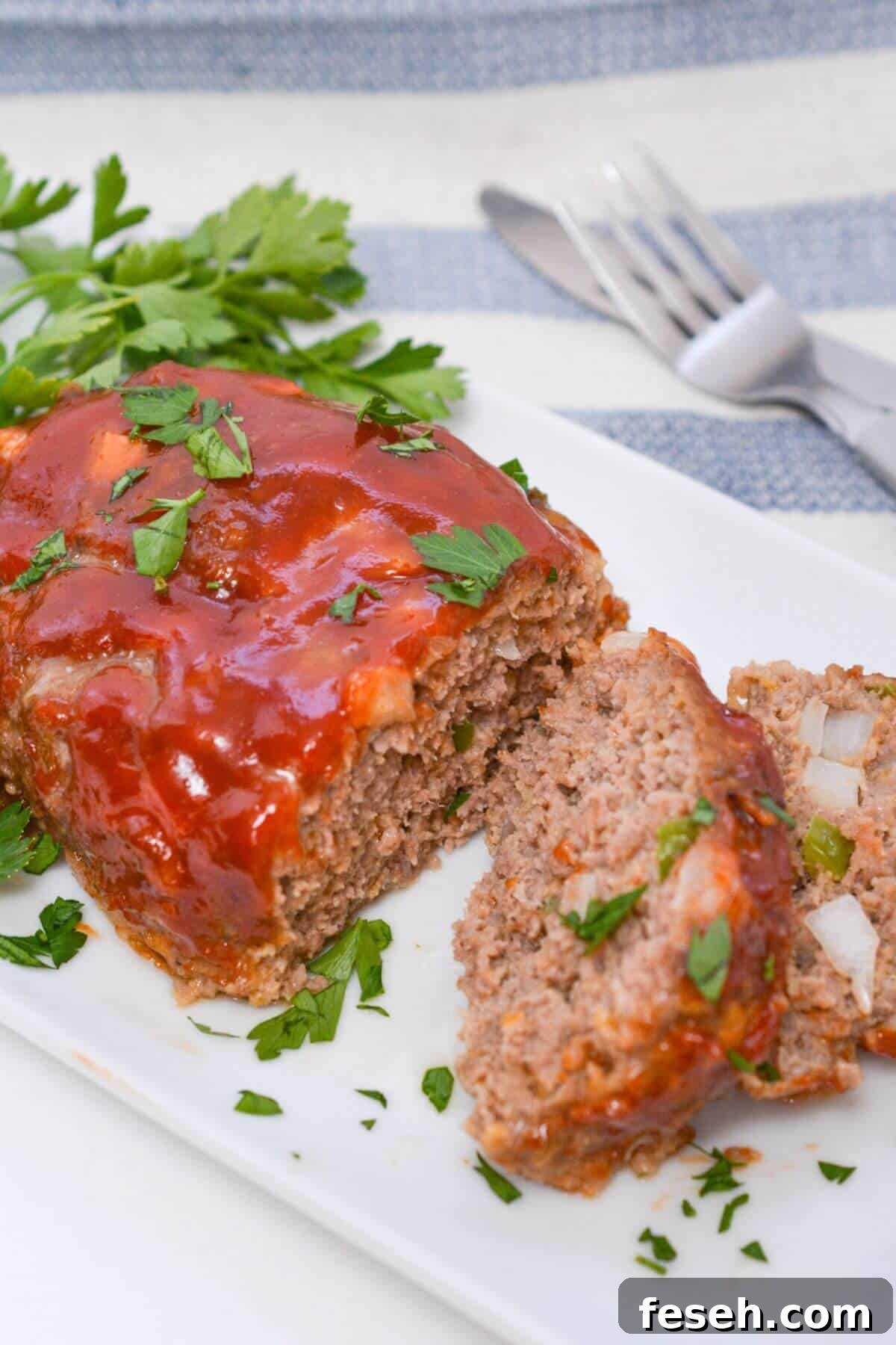 Meatloaf on a white platter with sauce and parsley.
