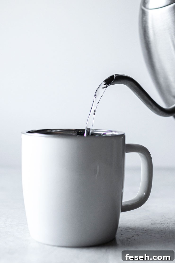Pouring hot water into a mug with tea.